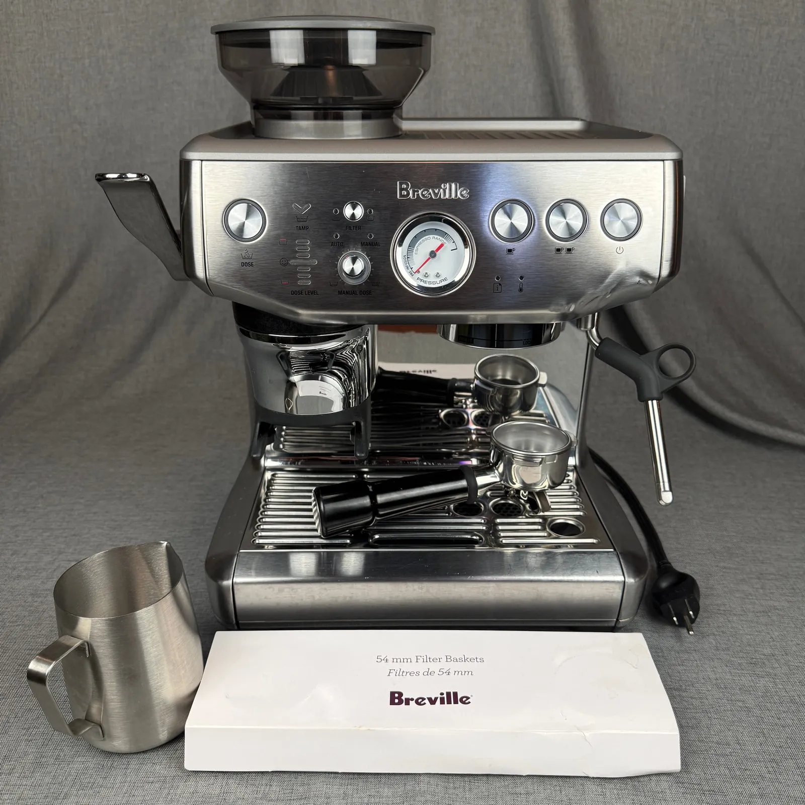 Breville Barista Express Impress espresso machine with its milk pitcher and filter baskets