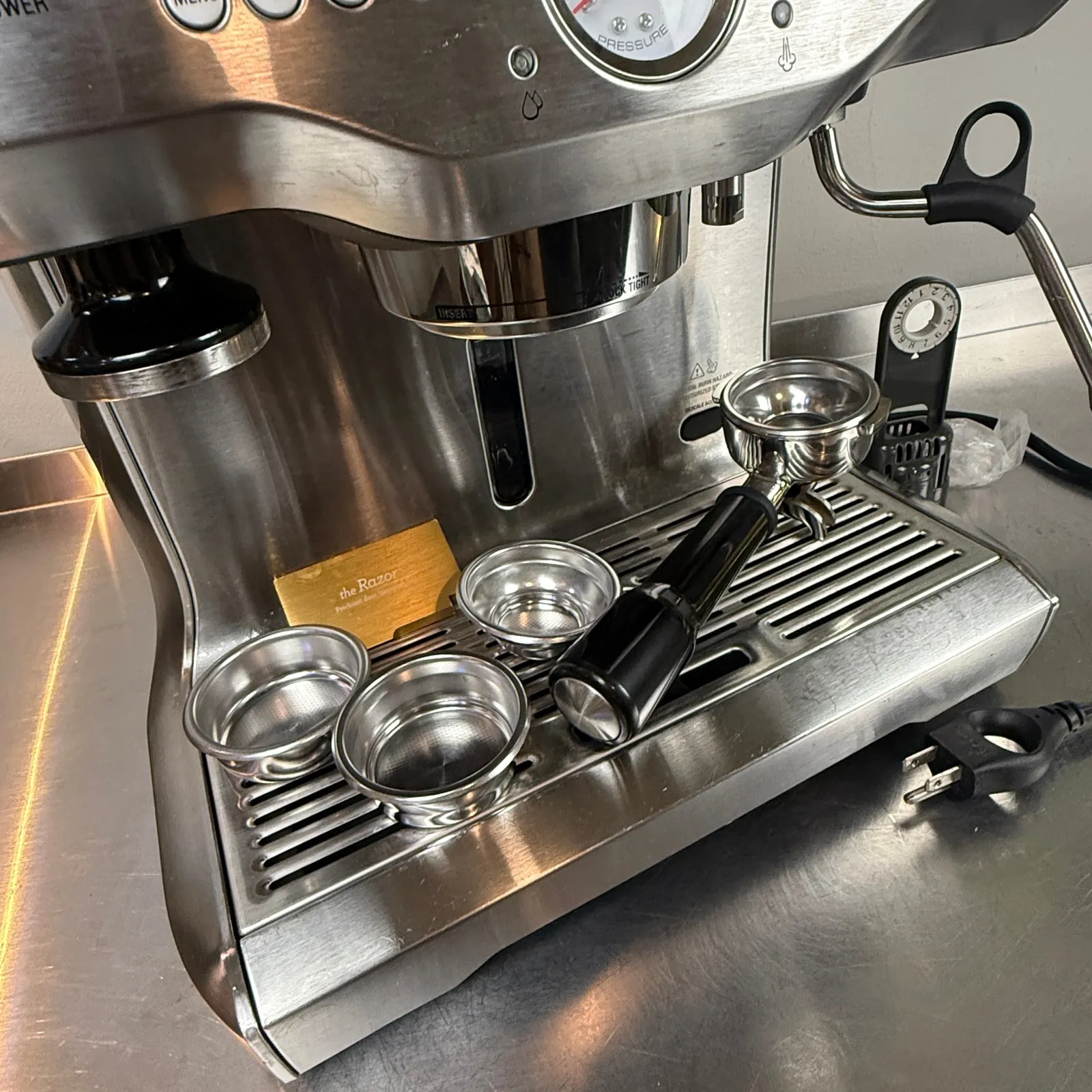 Close view of the Breville Dual Boiler’s group head, steam wand, portafilter and filter baskets